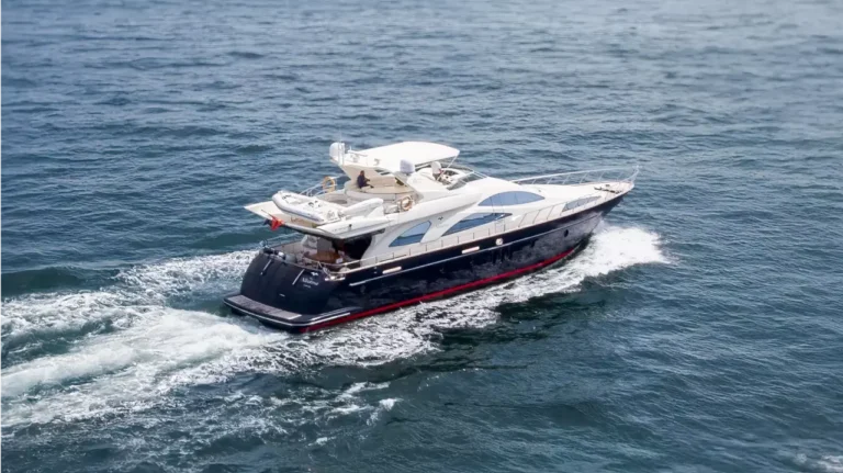 The sleek luxury yacht The Albatroz with a dark-colored hull and white superstructure cruises on calm waters near Vilamoura Marina, Portugal.