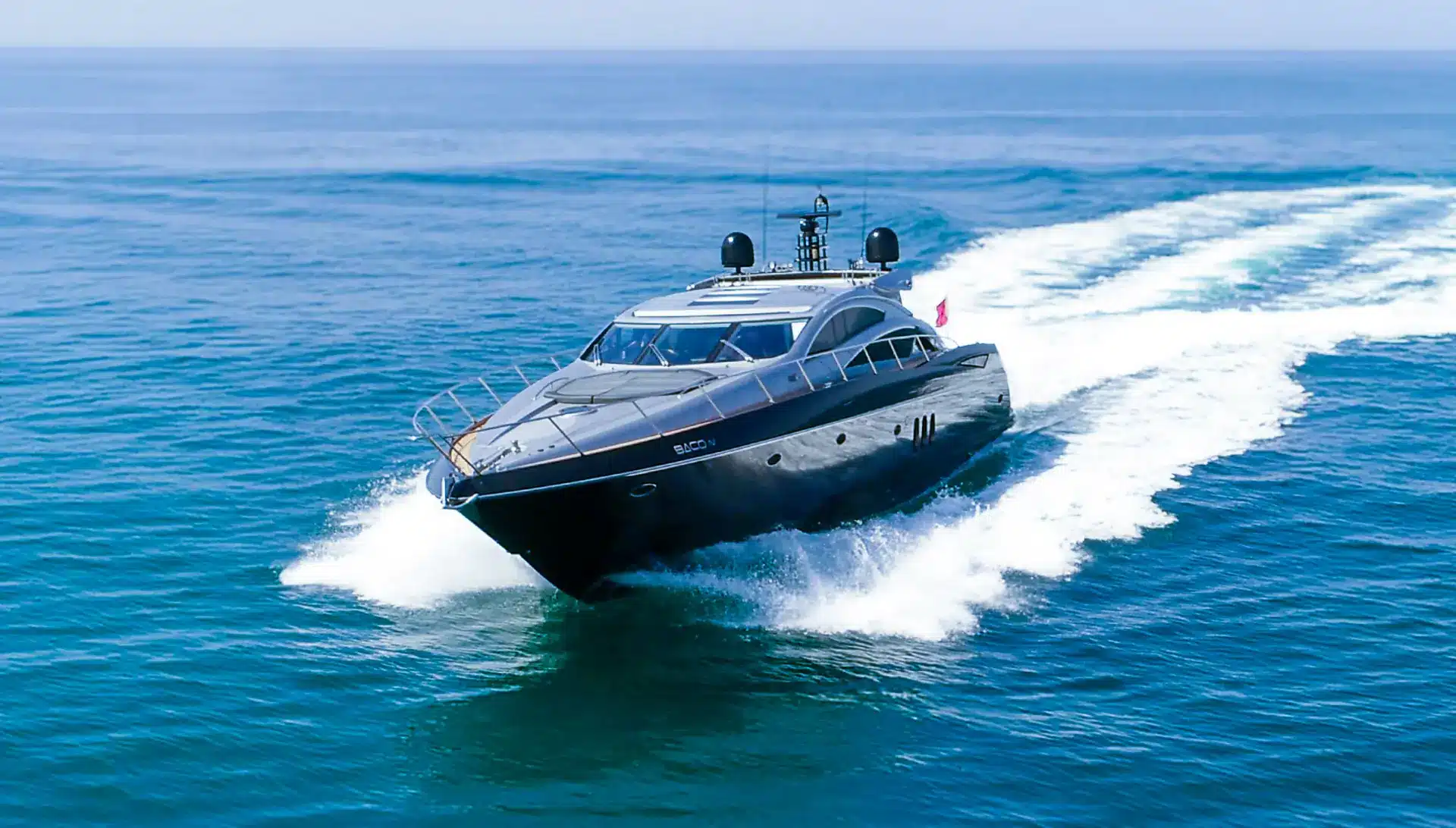 Luxury motor yacht Baco IV cruising at high speed on calm ocean waters with a sleek, modern design and powerful engines.