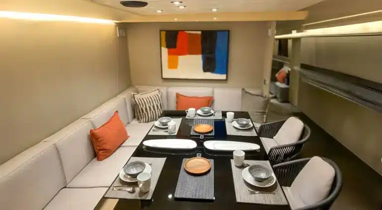 Modern well-appointed dining area on yacht Katerina XL at Cascais Marina, set for six with dark placemats, white plates, and elegant decor.