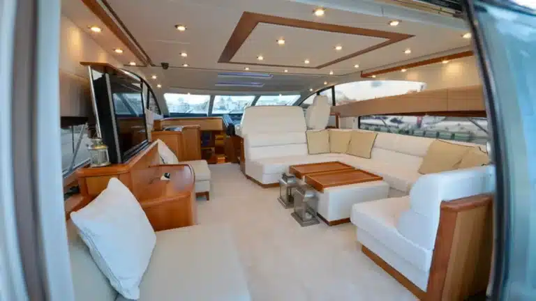 Spacious salon of luxury yacht Baco IV with white leather furniture, wood paneling, and elegant decor at Marina de Vilamoura.