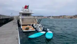 Luxury yacht Katerina XL moored at Cascais Marina in Portugal with paddleboards and houses in the background.