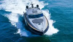 Luxury motor yacht Baco IV cruising fast on the open water near Marina de Vilamoura, emphasizing the sleek design against the blue ocean.