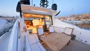 A dusk or dawn view of the deck on luxury yacht Baco IV at Marina de Vilamoura, featuring comfortable seating and a serene atmosphere.