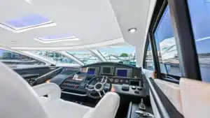 The Bridge of the yacht Baco IV docked at Marina de Vilamoura, showing high-tech control panels, digital displays, and white leather seats.