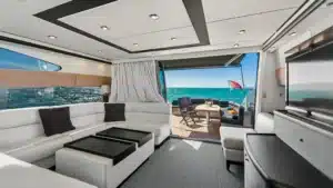 Interior cabin of the luxury yacht Baco IV at Marina de Vilamoura, featuring white leather seating, large windows, and modern amenities.