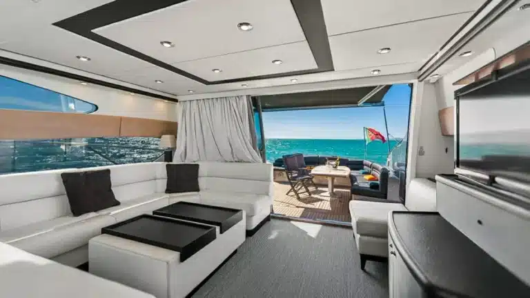 Interior cabin of the luxury yacht Baco IV at Marina de Vilamoura, featuring white leather seating, large windows, and modern amenities.