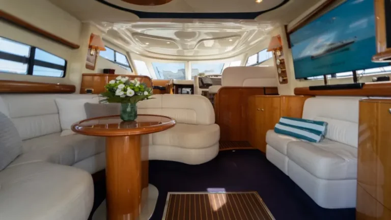 The elegant interior cabin of Mr Cliff yacht at Marina de Vilamoura, featuring white leather seating, wooden accents, and natural light for relaxation.