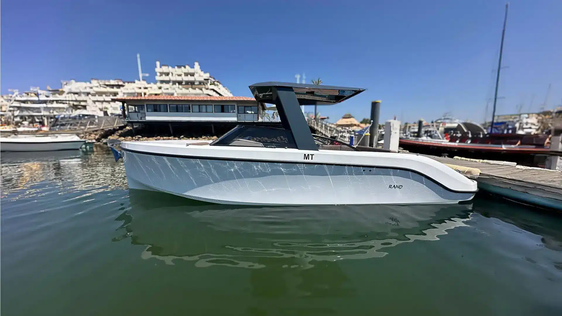 Majestic II, a sleek modern boat, moored at Marina de Vilamoura on a sunny day, with calm waters and other boats in the background.