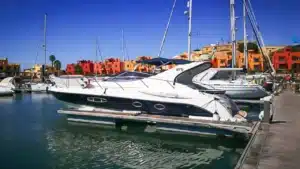 View of Marina de Portimão with several boats including the prominent yacht 'Atlantic 40', alongside colorful buildings and palm trees in the background.