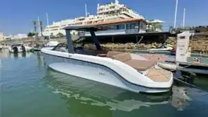 A sleek modern pleasure boat by RAND, docked in calm marina waters with a shaded area and comfortable seating.