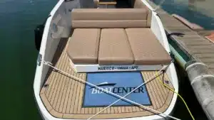 Rear view of a RAND yacht docked, featuring aft seating with brown cushions, teak-style deck flooring, and mooring ropes in a serene marina.