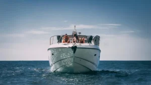 YOLO One luxury yacht with four people, cruising the clear waters near Marina de Vilamoura, Quarteira, Faro, Portugal.