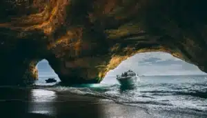 A stunning view from inside a sea cave with natural light, showing the YOLO One boat entering from the sea at Marina de Vilamoura.